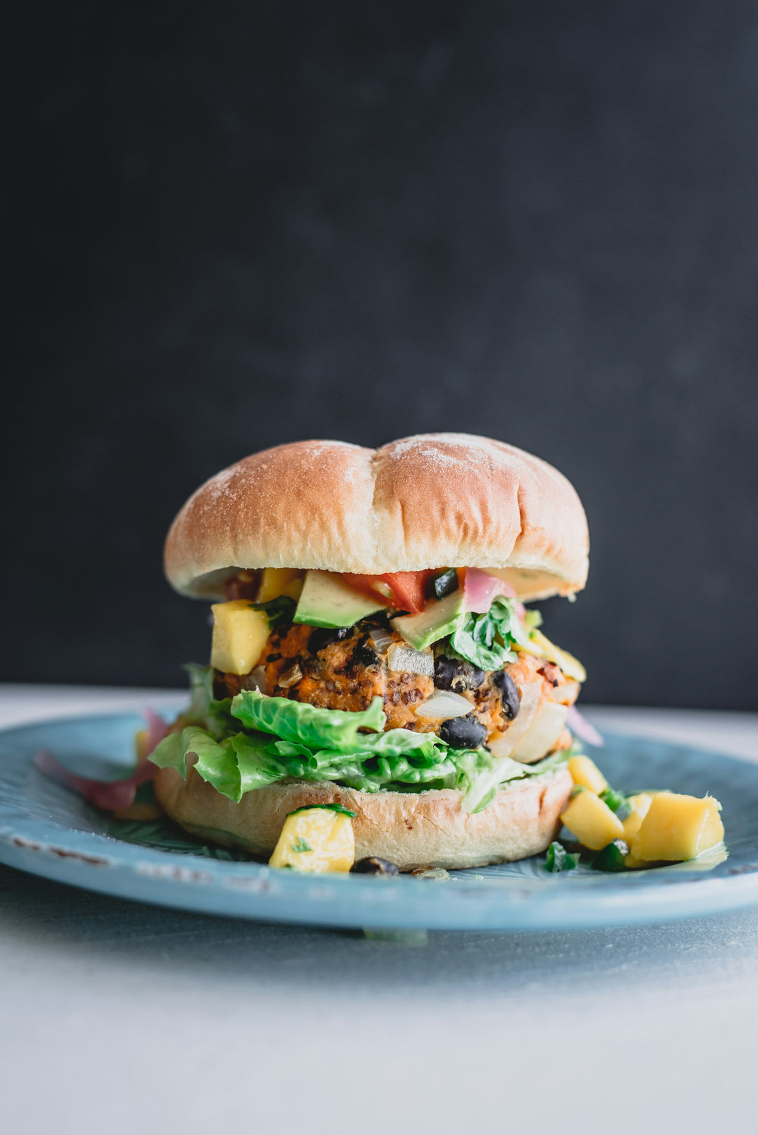 Veggie burger on a blue plate in front of a grey background